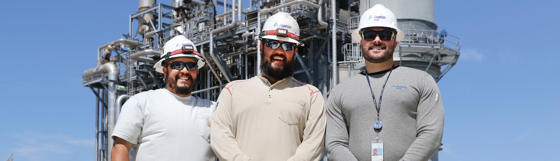 Austin Energy field workers smiling with utility infrastructure in the background