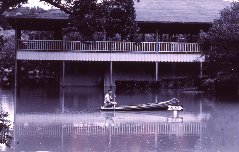 Man rows canoe through flooded street, 1935